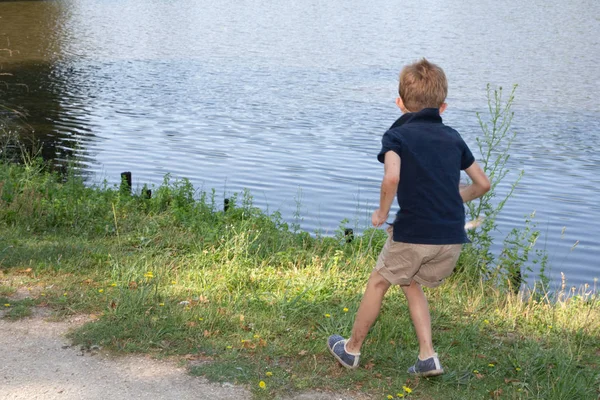 小男孩看着森林湖河景观玩鸟鸭 — 图库照片