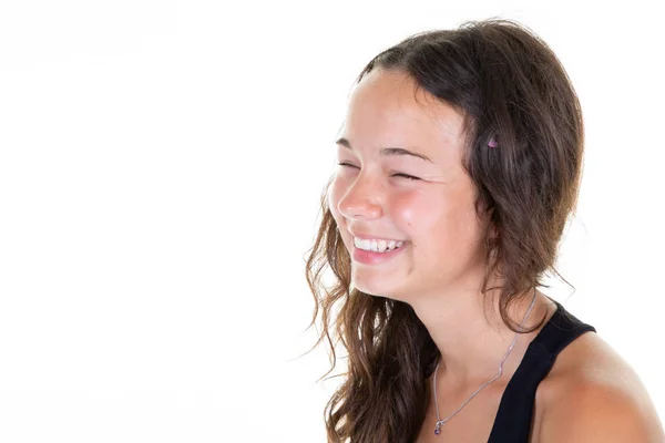 Positive emotions happy emotional teenage girl laughing eyes closed showing perfect white teeth while having fun indoors copy space white wall