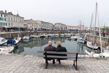 Saint Martin de Re, Charente Maritime / Fransa - 05 01 2019 : emekli çift kıdemli Island Ile de Re liman St Martin bankta oturup