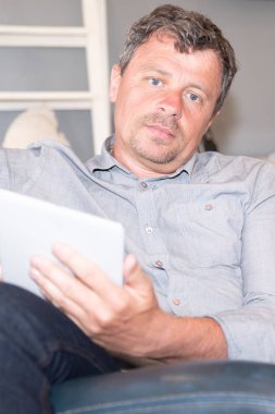 Yakışıklı adam evde tablet ile kanepede rahatlatıcı