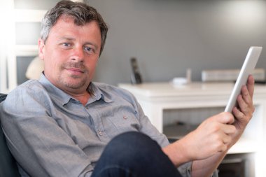 yakışıklı adam evde oturma odasında tablet üzerinde sörf rahatlayın