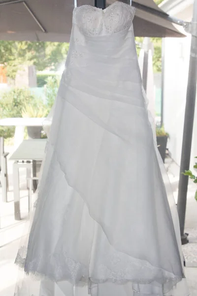 部屋の窓にハンガーに掛かる美しい白いウェディングドレス — ストック写真