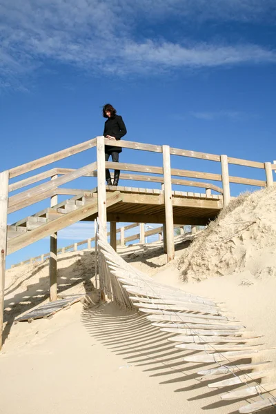woman in wooden staircase wood path with fence through dunes to the beach lacanau sea Atlantic coast