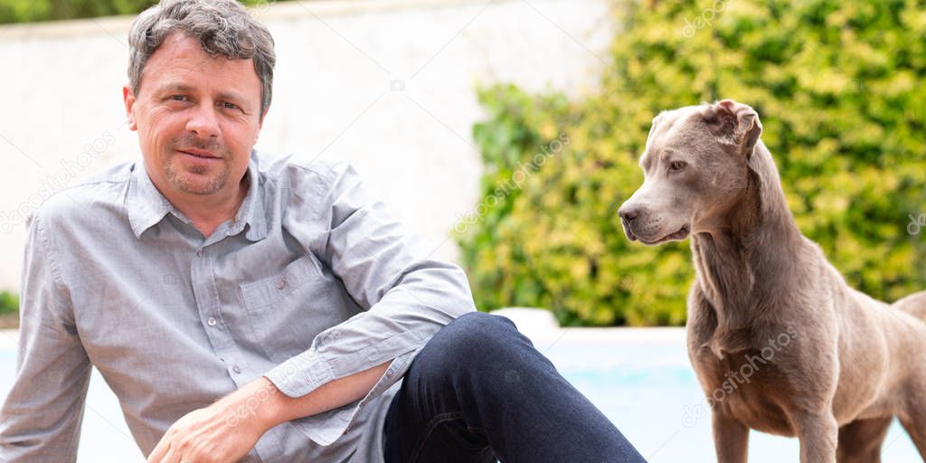 owner man posing with labrador retriever at home garden near pool