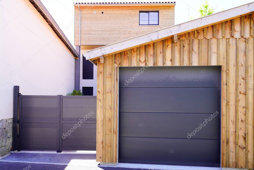 Aluminum modern home with grey gate portal and modern garage door of wooden house