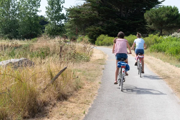 two girls ride bike in path bikeway in Ile de noirmoutier island in France Vendee