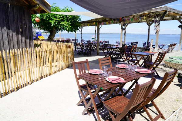 キャップフェレフランスの典型的な村の空の椅子と木製のテーブルと海辺のビーチテラスカキレストラン — ストック写真