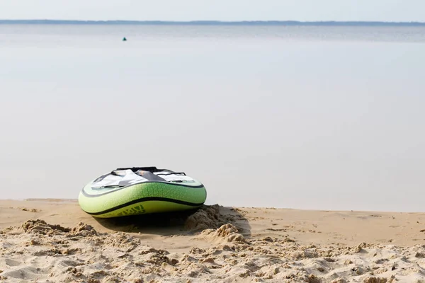 レイクサイドのビーチ湖の水の近くの砂に寝そべっているパドルボードを — ストック写真