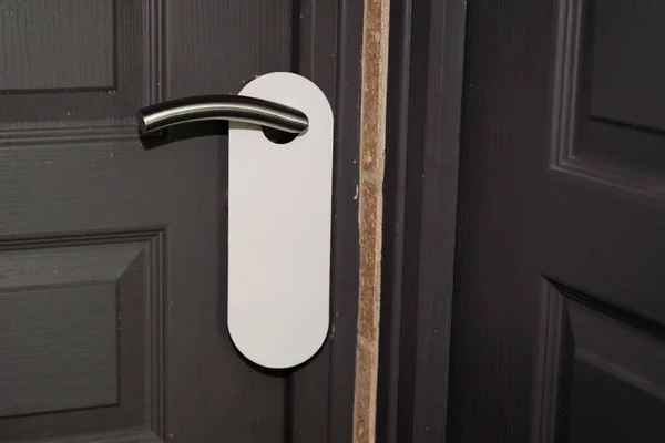 White door hanger on grey classic door with empty label do not disturb real