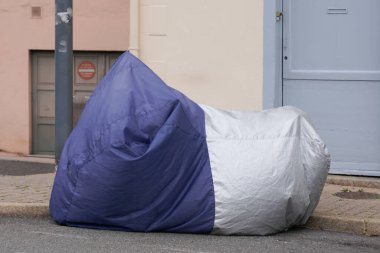 Motosiklet, gümüş ve mavi kaplamalarla korunuyor. Motosiklet, branda ceketli.