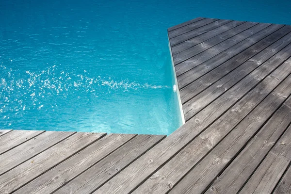 在柚木地板上配备异国情调木制平台的现代蓝色游泳池 — 图库照片