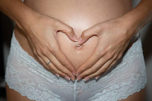 怀孕期间有心脏手的孕妇腹部 — 图库照片