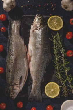 Biberiyeli taze çiğ alabalık, domates, sarımsak, biber, tuz ve limon. Sağlıklı Akdeniz yemekleri ve diyet konsepti, üst görünüm, düz yatış.