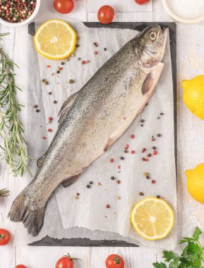 Biberiyeli taze çiğ alabalık, kirazlı domates, maydanoz, biber, tuz ve limon. Sağlıklı Akdeniz yemekleri ve diyet konsepti, üst görünüm, düz yatış.