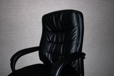 Siyah deri ofis koltuğu, gri arka plana yakın.