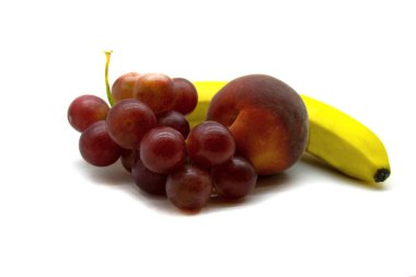 Bir demet üzüm, olgun bir şeftali ve beyaz bir arka planda izole edilmiş muz yakın plan.