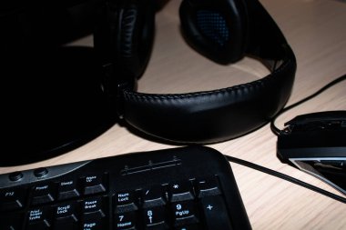 Bir ışık masasında bilgisayar klavyesi, kulaklık ve optik fare yakın plan