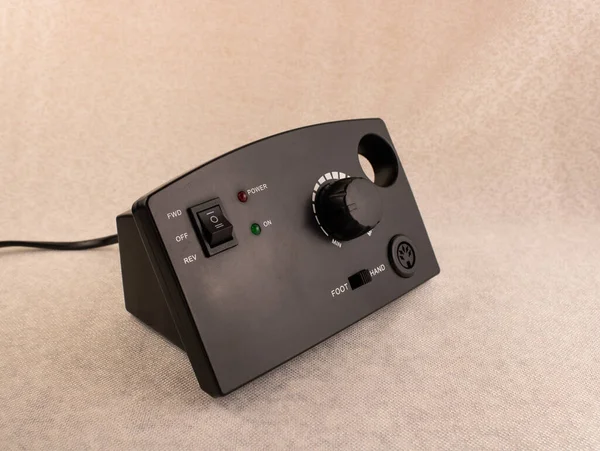 Bej arka planda siyah manikür ve pedikür makinesi.