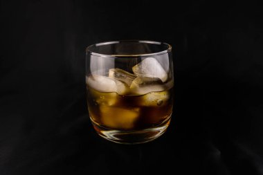 Koyu arkaplanda cam bir fincanda buzlar olan canlandırıcı bir içecek.