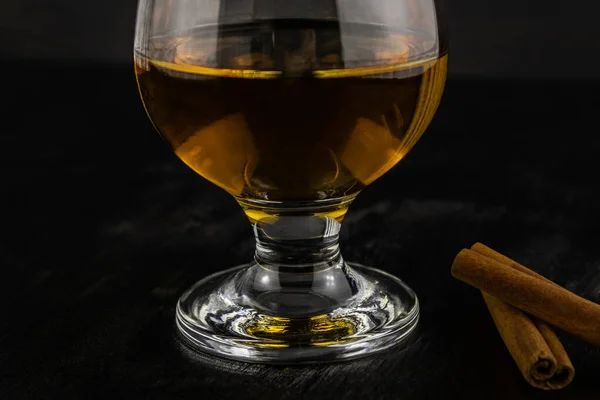 Een Glas Cognac Kaneelstokjes Close Een Donkere Houten Ondergrond — Stockfoto