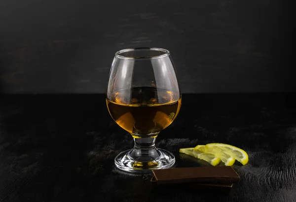 Glass Cognac Chocolate Lemon Slices Close Dark Wooden Background — Stock Photo, Image