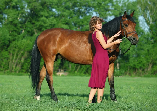 美しいですモデル女の子リード彼女の馬で牧草地に日没 — ストック写真