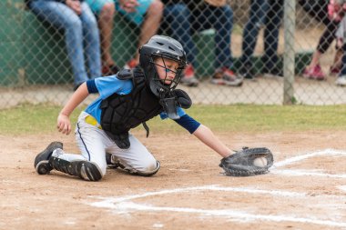 Tebeşir bulutu çamura bir düşük pitch için lunging çevik küçük lig beyzbol catcher.