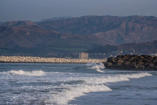 Distant hotel visible in the far distance, across several beaches and jettys in the coastal town of Ventura.