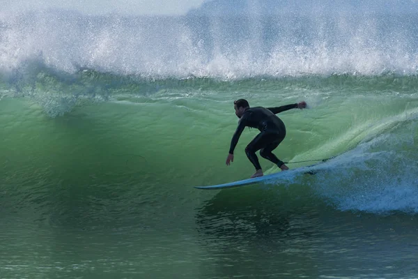 Surfista Fato Mergulho Preto Retroiluminado Enquanto Arrasta Mão Pela Onda — Fotografia de Stock