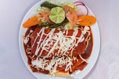 Lezzetli Meksika yemekleri için sıcak bir tabakta servis edilen pirinçli ve fasulyeli ıslak Ranchero Burrito manzarası..