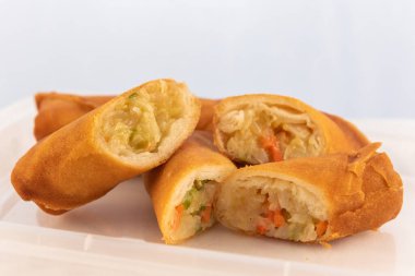 Yanında dilimlenmiş yumurtalı börek var. Yağda kızartılmış rulo gibi görünüyor..