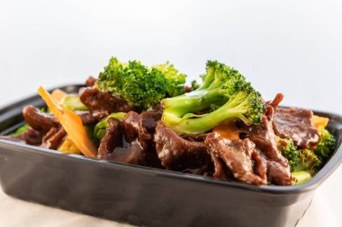 Büyük bir kase brokolili biftek, tatlı sos, et ve sebzelerin pırıltısını gösteriyor..