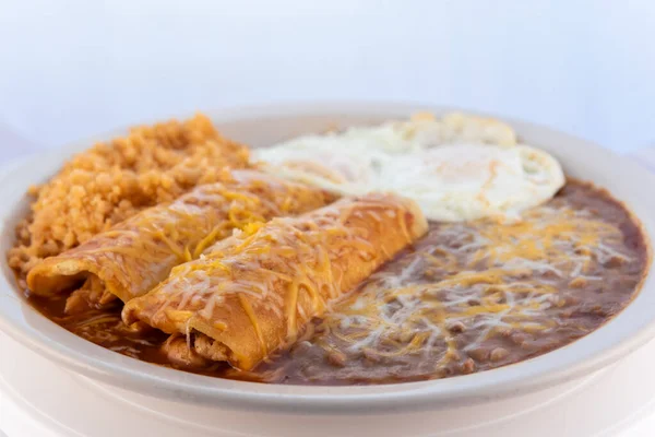 Sıcak bir kahvaltı enchilada 'sı, kızarmış fasulye, pilav ve yumurta ile birlikte cömertçe servis edilir..