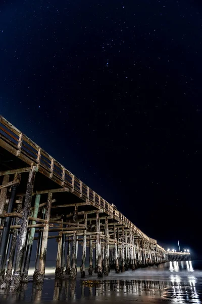 ヴェントゥラ桟橋の下の太平洋の水に反射する桟橋のランプ上の空のオリオン座とレプス星 — ストック写真