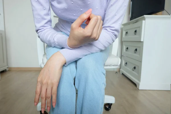 Close Up Pink Nail Polish on Women\'s Hand. Woman in Overcoat and Pink Nails Manicure. A Beautiful Woman Sitting on White Chair in White Room Studio Background