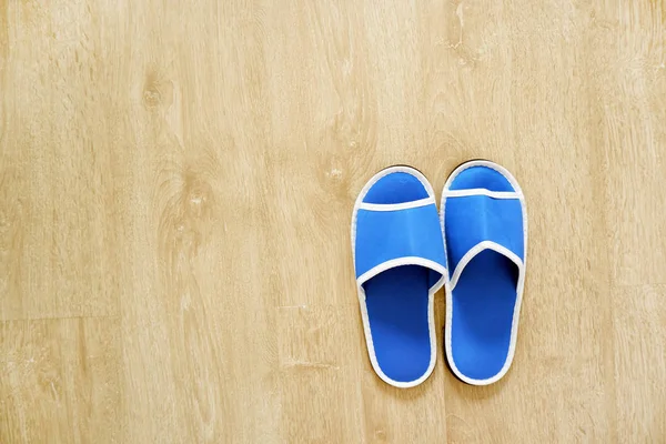 Pair of Blank Blue House Slippers Isolated from Hotel. Woman Bed Shoes, Clear Warm Sandal Over Wood at Bedroom. Soft Comfortable Home Footwear on Wooden Floor Background, Top View.