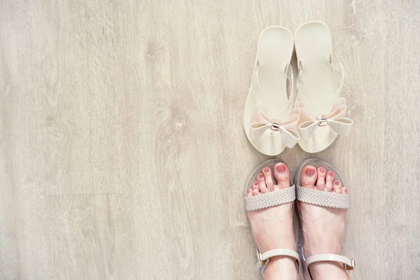 Close Up on Woman is Feet Wearing Bow Shoes Isolated on Wood Floor, Fashionable Accessories. Fashion Flat Shoe (Footwear). Selfie of Feet in Nude Sandals Standing on Wooden Background, Top View.