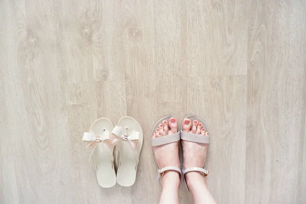 Close Up on Woman is Feet Wearing Bow Shoes Isolated on Wood Floor, Fashionable Accessories. Fashion Flat Shoe (Footwear). Selfie of Feet in Nude Sandals Standing on Wooden Background, Top View.