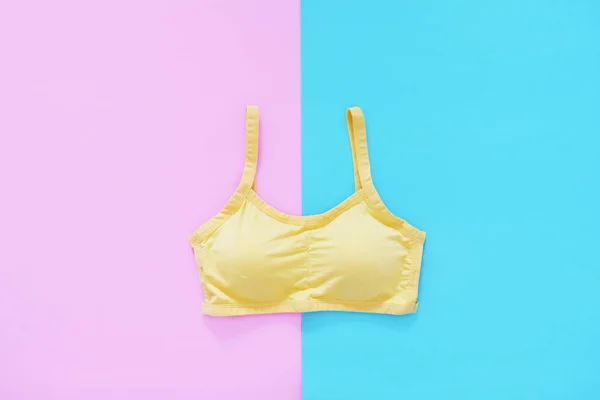 Top View of Sportswear Clothing. Women is Yellow Sports Bra Isolated on Blue and Pink Color Pastel. Sport Accessories and Fashion, Healthy Lifestyle. Sport Clothes on Two Tone Background, Copy Space.