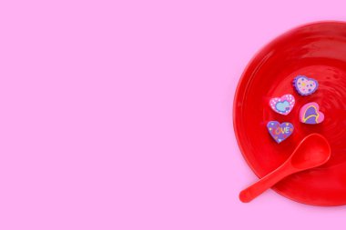 Sevgililer günü renkli kalp kırmızı plaka ve aşk kavramı için kaşık var. Düz silgi ile romantik bir kalp şeklinde. Pastel pembe Kağıt arka plan üzerinde izole farklı lastik kalp simgesi.