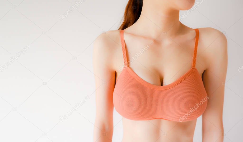 Woman is Breast in Orange Underwear Posing on Grey Background,Show Bra. Cropped Close Up of Sexy Female Wearing Sport Bra (Sportswear) with Perfect Chest. Fitness and Yoga Healthy Lifestyle Concept.