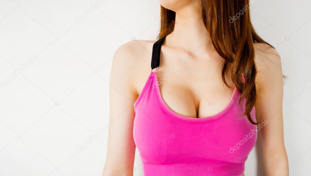 Bra. Woman is Breast in Pink Underwear Posing on Grey or White Background. Cropped Close Up of Sexy Female Wearing Sport Bra (Sportswear) with Perfect Chest. Fitness and Yoga Healthy Lifestyle Concept.