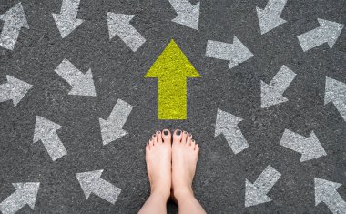 Feet and Arrows on Road. Woman Bare Feet with Gray Nail Polish Manicure Standing on Grunge Concrete with Many White Arrow Sign and Yellow Sign Go Straight. Future Life with Many Direction Symbol. clipart