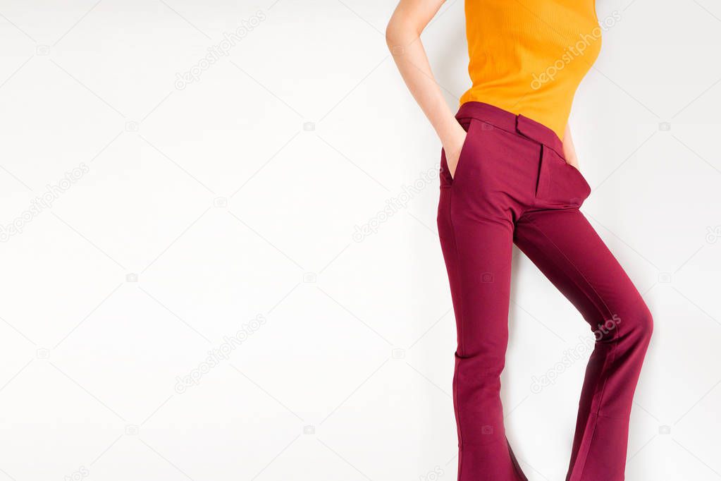 Pants. Beautiful Young Woman in Red or Carmine Pants and Yellow Shirt Posing on Gray Background. Asian Female Sexy Slim Body and Standing on White Studio. Fashion and Lifestyle for Summer Concept.