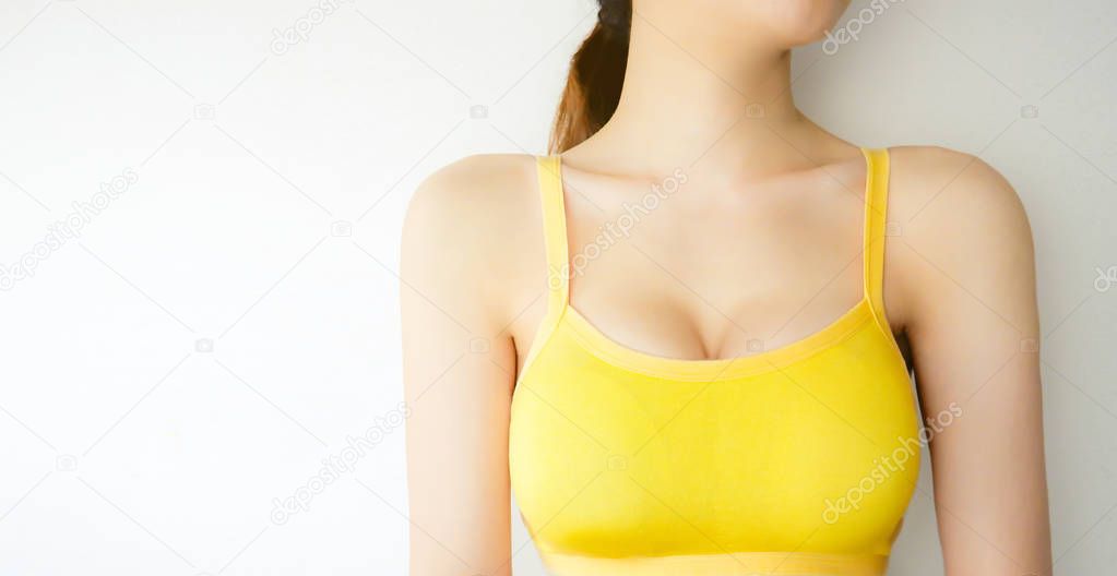 Woman is Breast in Yellow Underwear Posing on Grey Background,Show Bra. Cropped Close Up of Sexy Female Wearing Sport Bra (Sportswear) with Perfect Chest. Fitness and Yoga Healthy Lifestyle Concept.