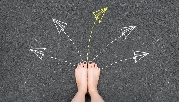 Solution. Selfie woman feet with gray nail polish manicure standing on road with rocket paper and many arrows sign choice. Success, creative and idea concept. Future life. Foot and yellow arrow.