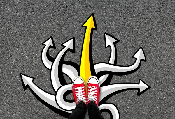 Feet and many arrows on road background. Pair of foot standing on concrete with color graffiti arrow sign choices, creative and idea concept. Red sneakers on tarmac road with yellow sign go straight.