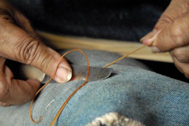 Manos de artesano cosiendo trabadaddo con fibra veal