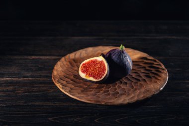 Siyah bir ahşap zemin üzerine bir plaka üzerinde bir kaç incir. Meyve şifa