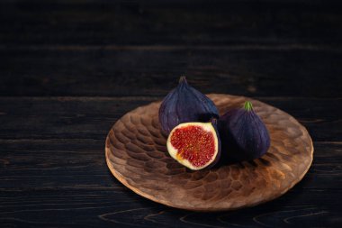 Siyah bir ahşap zemin üzerine bir plaka üzerinde bir kaç incir. Meyve şifa